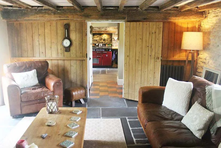 View from the living room through the hallway towards the kitchen, showing Victorian floor tiles and wooden panelling.