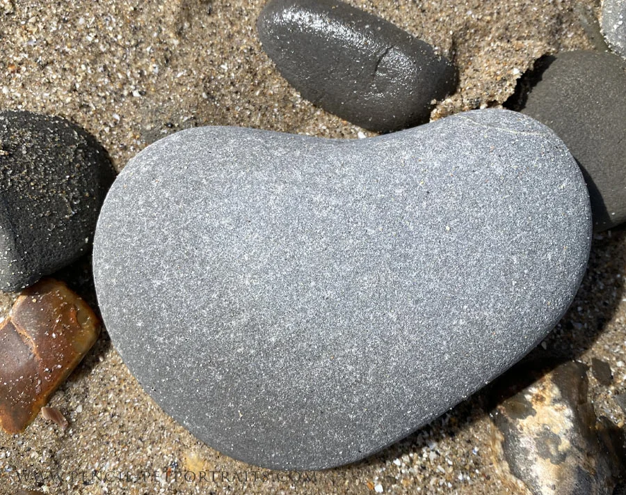 Smooth stones arranged into the shape of a heart on a beach.