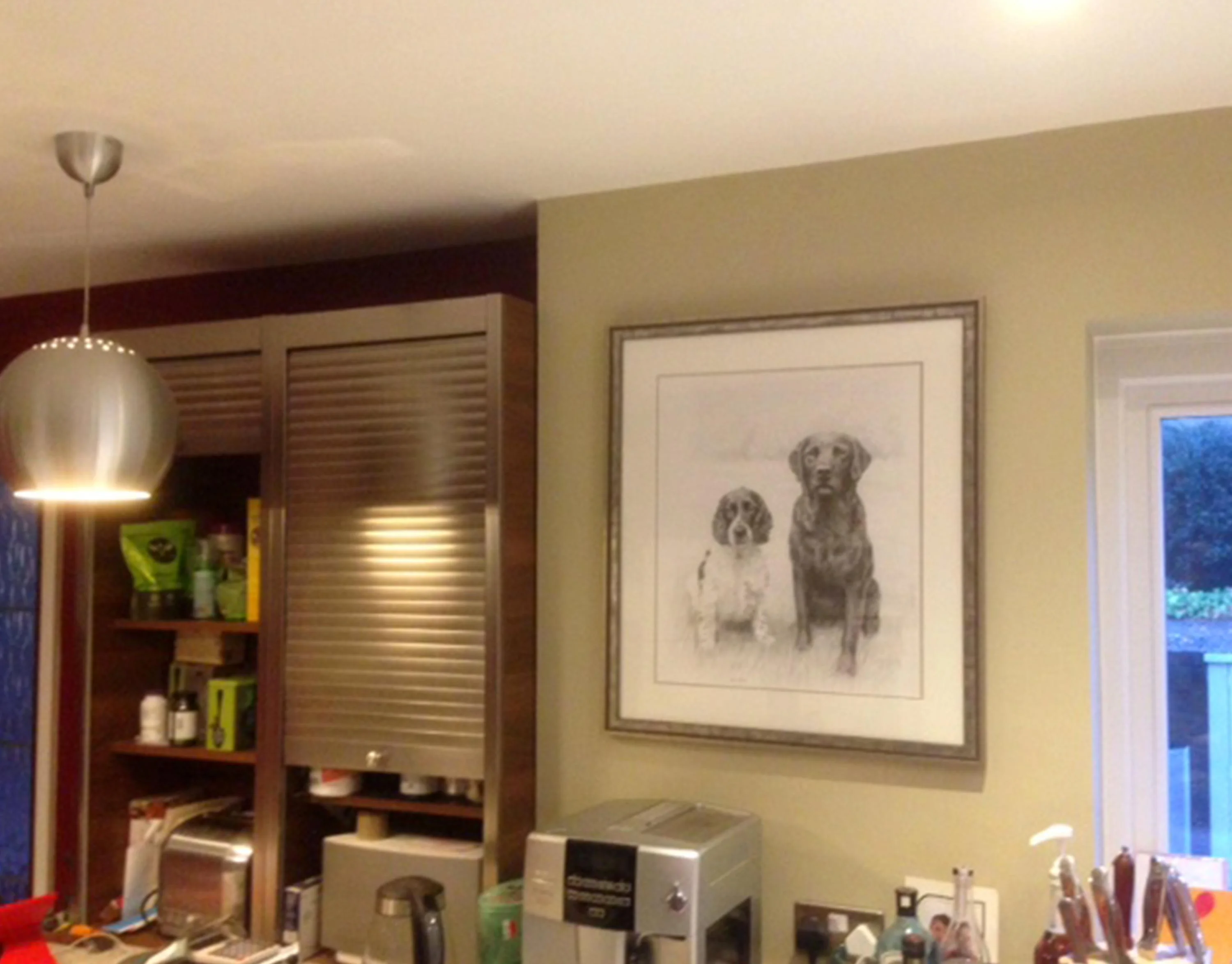 The framed pencil portrait of Stanley and Jarvis hanging on a kitchen wall.