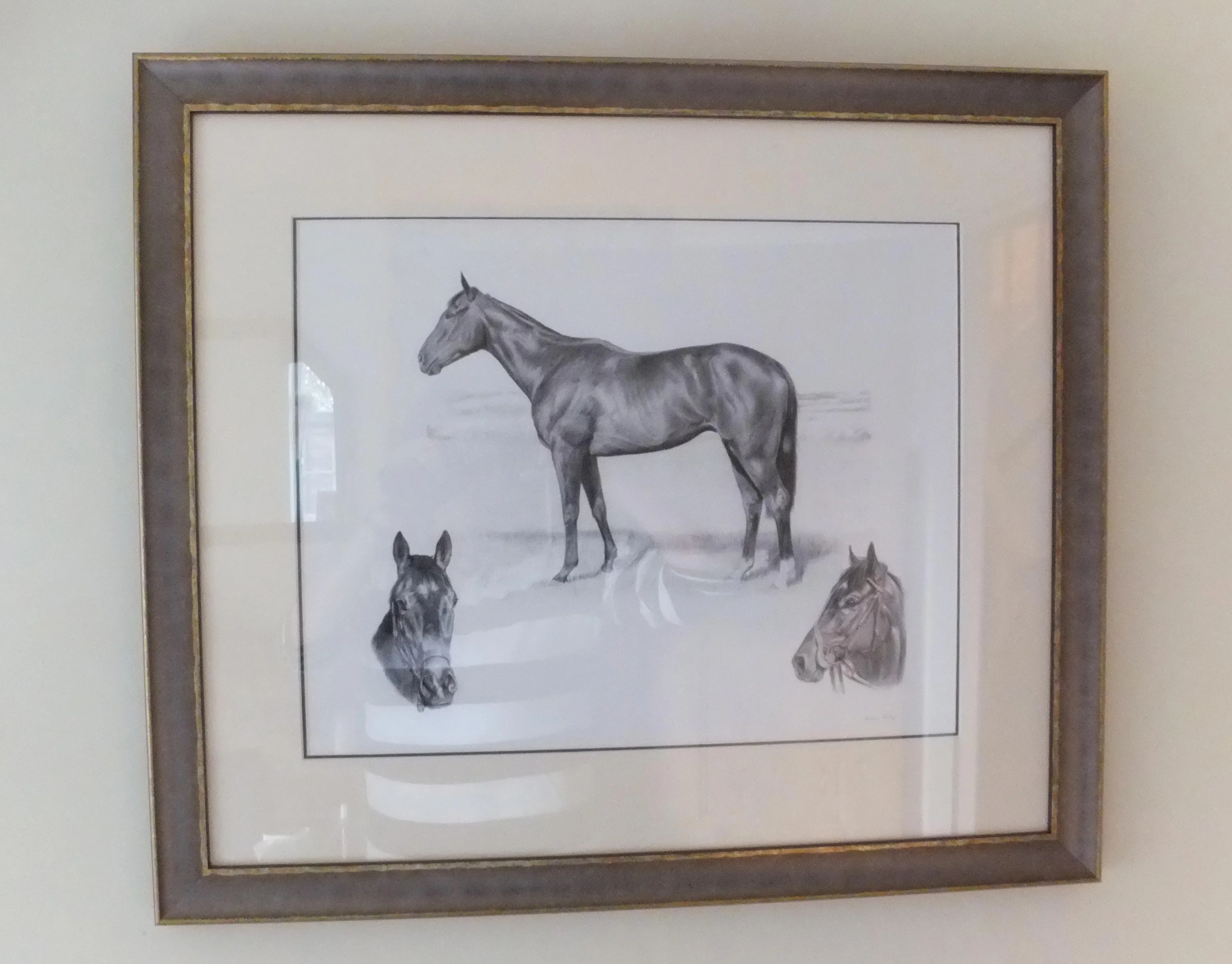 A framed print of the racehorse Charles pencil portrait hanging on a wall.